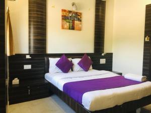 una camera da letto con un grande letto con cuscini viola di Hotel Amber-colaba a Mumbai