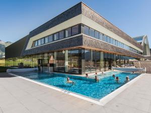 a group of people in a swimming pool in front of a building at Narzissen Vital Resort Bad Aussee in Bad Aussee