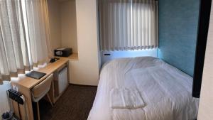 a hotel room with a bed and a desk and a bed sidx sidx sidx at Remington Hotel in Akashi