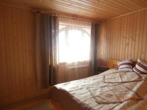 1 dormitorio con 1 cama y una ventana con cortinas en Karpatskiy Domyk, en Izky