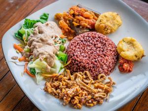 a plate of food that includes meat, vegetables, and rice at Serenity Eco Guesthouse - CHSE certified in Canggu