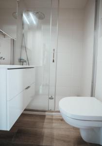 La salle de bains blanche est pourvue d'une douche et de toilettes. dans l'établissement Appartement Val Rose II, 11de verdieping, à Blankenberge