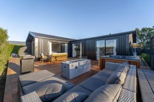 un patio trasero con una casa negra con sofá en Black Barn Modern: Luxe Martinborough Escape en Martinborough 