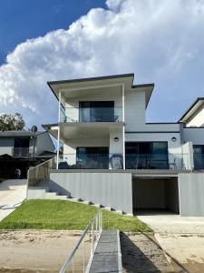 a large white house with stairs in front of it at Reflections on the water in Port Macquarie