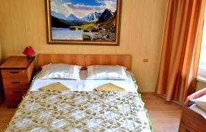 a bedroom with a bed with a picture on the wall at Domik u Plyazha Guest House in Gelendzhik