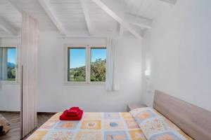 a white bedroom with a bed and two windows at Casa Vacanze Porto Istana in Murta Maria