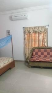 een slaapkamer met een bed en een raam met een gordijn bij Irini's apartment in Cotonou