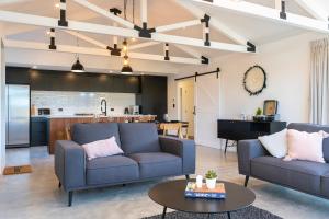 a living room with two blue couches and a kitchen at Black Barn Modern: Luxe Martinborough Escape in Martinborough 