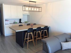 a kitchen with a large island with bar stools at Appartement Val Rose II, 7de verdieping in Blankenberge