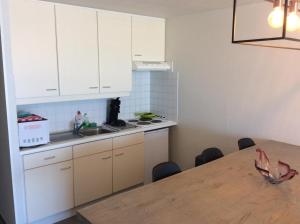 a kitchen with white cabinets and a wooden table at Appartement Val Rose II, 7de verdieping in Blankenberge