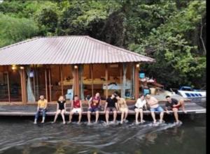 a group of people sitting on a dock in the water at Kodaun River Kwai Resort in Kanchanaburi