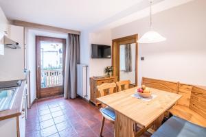 uma cozinha e sala de jantar com uma mesa de madeira e cadeiras em Apartments Heidenberger Delle Scuole em Colle Isarco