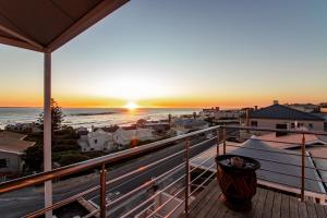 a view of the sunset from the balcony of a house at Blaauw Village Guest House in Bloubergstrand