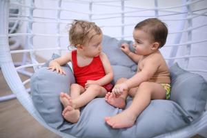 dois bebés sentados numa cama de aros em Nádas Tó Park Hotel em Vasad