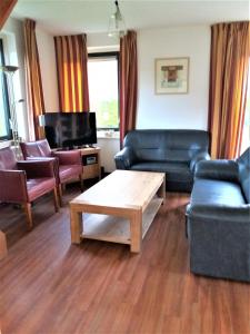 uma sala de estar com mobiliário de couro e uma mesa de centro em Vacation Home 23 em Tzummarum