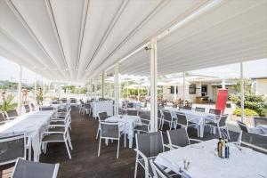 un restaurant avec des tables et des chaises blanches sous un auvent blanc dans l'établissement Grand Hotel Cesenatico, à Cesenatico