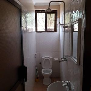 a bathroom with a toilet and a sink and a window at Prideinn Lodge Kigamboni in Dar es Salaam