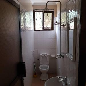 a bathroom with a toilet and a sink and a window at Prideinn Lodge Kigamboni in Dar es Salaam +18 photos