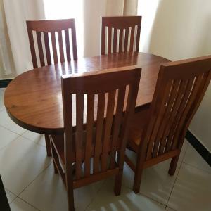 een houten tafel met drie stoelen en een houten tafel en een tafel en stoelen bij Prideinn Lodge Kigamboni in Dar es Salaam