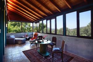 uma sala de estar com uma mesa, cadeiras e janelas em Villa Areti - A Cottage in the Cretan Nature em Kántanos