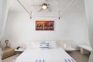 a white bedroom with a bed and a ceiling fan at Port Alacati Hotel in Alacati