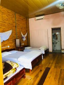 een slaapkamer met 2 bedden in een kamer met houten vloeren bij Ba Be Lake View Homestay in An Ma