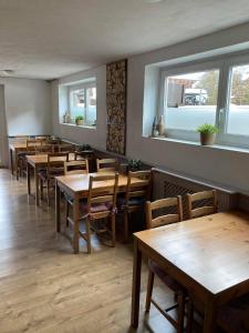 een restaurant met houten tafels, stoelen en ramen bij Pension AdlerHorst in Steindorf am Ossiacher See