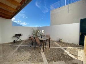 d'une terrasse avec une table, des chaises et un mur. dans l'établissement casa nuria, en el centro, al lado de la escalinata del calvario para 6 personas, à Pollença