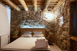 Un dormitorio con una pared de piedra y una cama. en Masovería l'Era, en Arbúcies