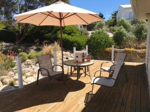 a table and chairs with an umbrella on a deck at Kangaroo Pause Holiday home at Clayton Bay in Clayton Bay