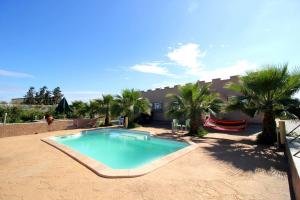 a swimming pool in a yard with palm trees at Maison d hôtes Bungalow Villa Hammam Bien-être et Piscine in Agadir