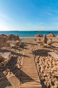 un camino de madera en una playa con sillas y sombrillas en Hotel Christina en La Canea
