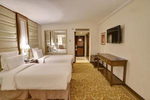 a hotel room with two beds and a desk and a television at Pearl Continental Hotel, Karachi in Karachi