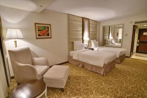 ein Hotelzimmer mit 2 Betten und einem Stuhl in der Unterkunft Pearl Continental Hotel, Karachi in Karatschi