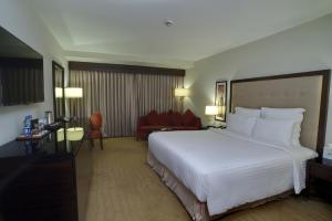 a hotel room with a large white bed and a couch at Pearl Continental Hotel, Karachi in Karachi