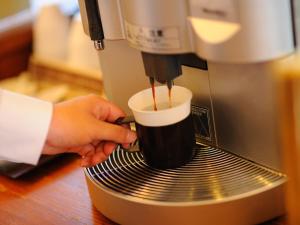 une personne prépare une tasse de café dans une machine à expresso dans l'établissement Hotel Route-Inn Court Kashiwazaki, à Kashiwazaki