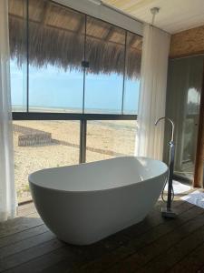 a white bath tub sitting in front of a window at BobZ Boutique Resort in Barra Grande