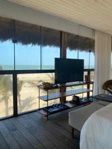 Dormitorio con cama, TV y playa en BobZ Boutique Resort en Barra Grande