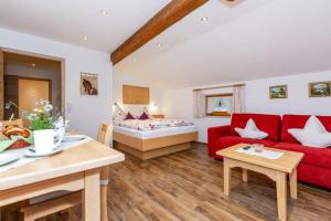 een woonkamer met een rode bank en een bed bij Feichtenhof in Reit im Winkl