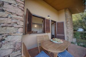 a table and chairs on a patio with a stone wall at Residence Oasi e Oasi Blu in San Teodoro
