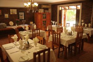 un restaurante con mesas y sillas blancas y una lámpara de araña en Ngwenya Boutique Hotel, en Lephalale