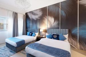 ein Hotelzimmer mit 2 Betten und blauen Kissen in der Unterkunft Exclusive Escapes Private Pool Homes and Villas by GLOBALSTAY Holiday Homes in Dubai