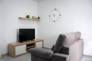 een woonkamer met een stoel en een klok aan de muur bij Apartamento Calma in Vejer de la Frontera