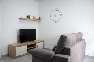 a living room with a chair and a clock on the wall at Apartamento Calma in Vejer de la Frontera