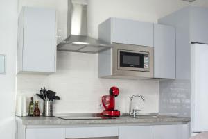 a kitchen with white cabinets and a red mixer at Apartamento Calma in Vejer de la Frontera +5 photos