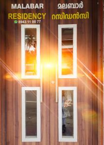 a woman standing in front of a building with three windows at MALABAR Residency in Perintalmanna