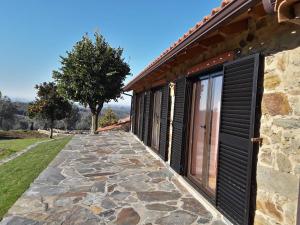 a stone walkway next to a building with black doors at A casa do Moinho in Pedrógão Pequeno