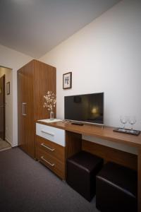 a room with a desk with a television and a cabinet at Penzion Hastrman in Banská Bystrica