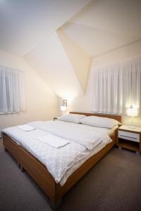 1 dormitorio con 1 cama grande, 2 mesas y 2 lámparas en Penzion Hastrman en Banská Bystrica
