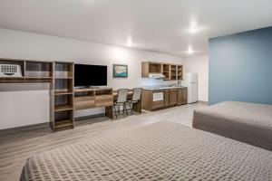 Habitación de hotel con 2 camas y escritorio con TV. en WoodSpring Suites Detroit Farmington Hills, en Farmington Hills